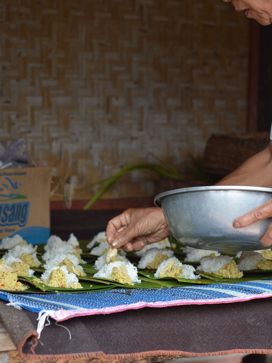Hands preparing banana-leaf offerings
