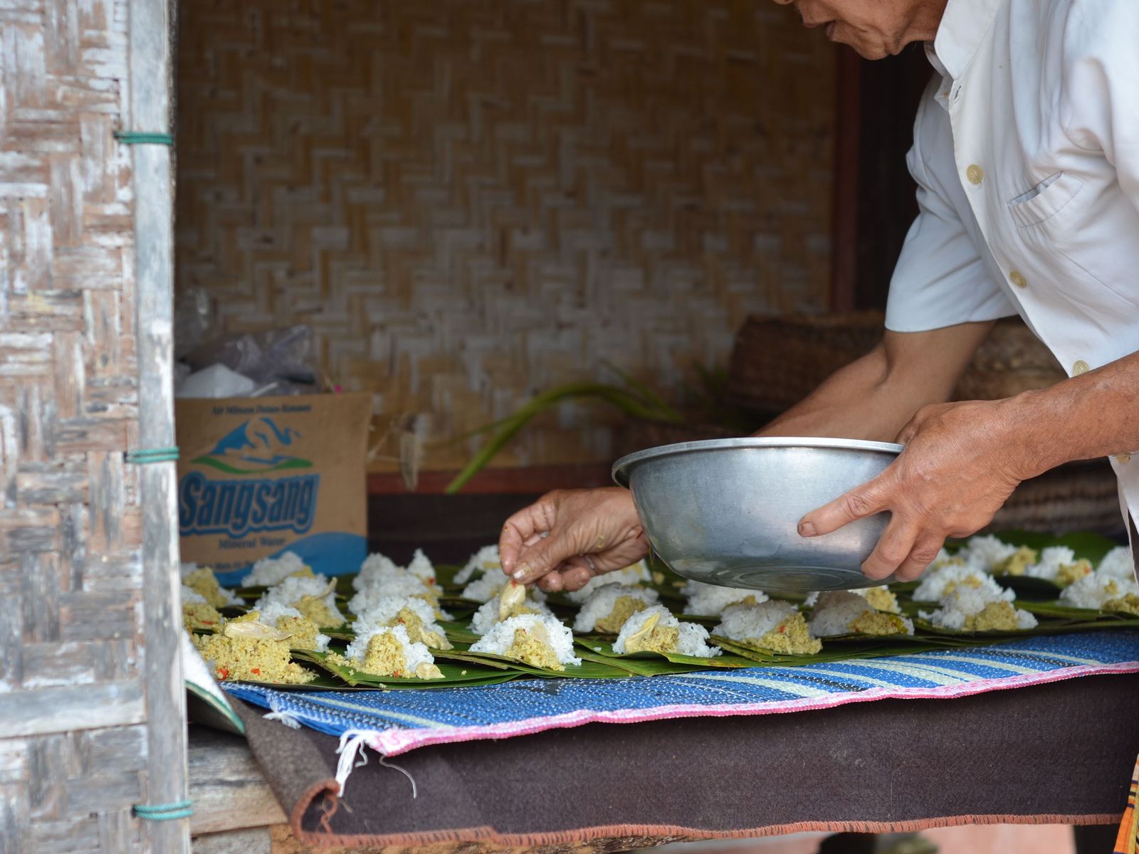 Hands preparing banana-leaf offerings