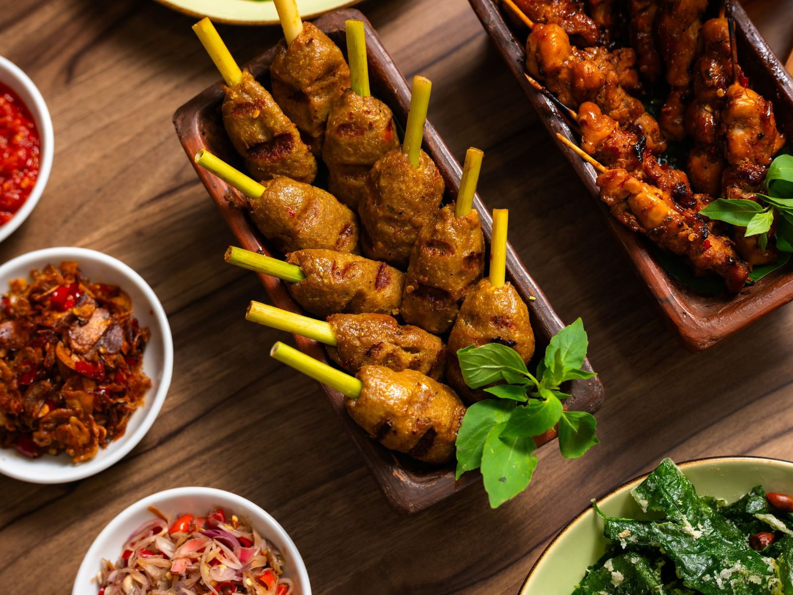 Sate lilit on lemongrass sticks with sambal and greens