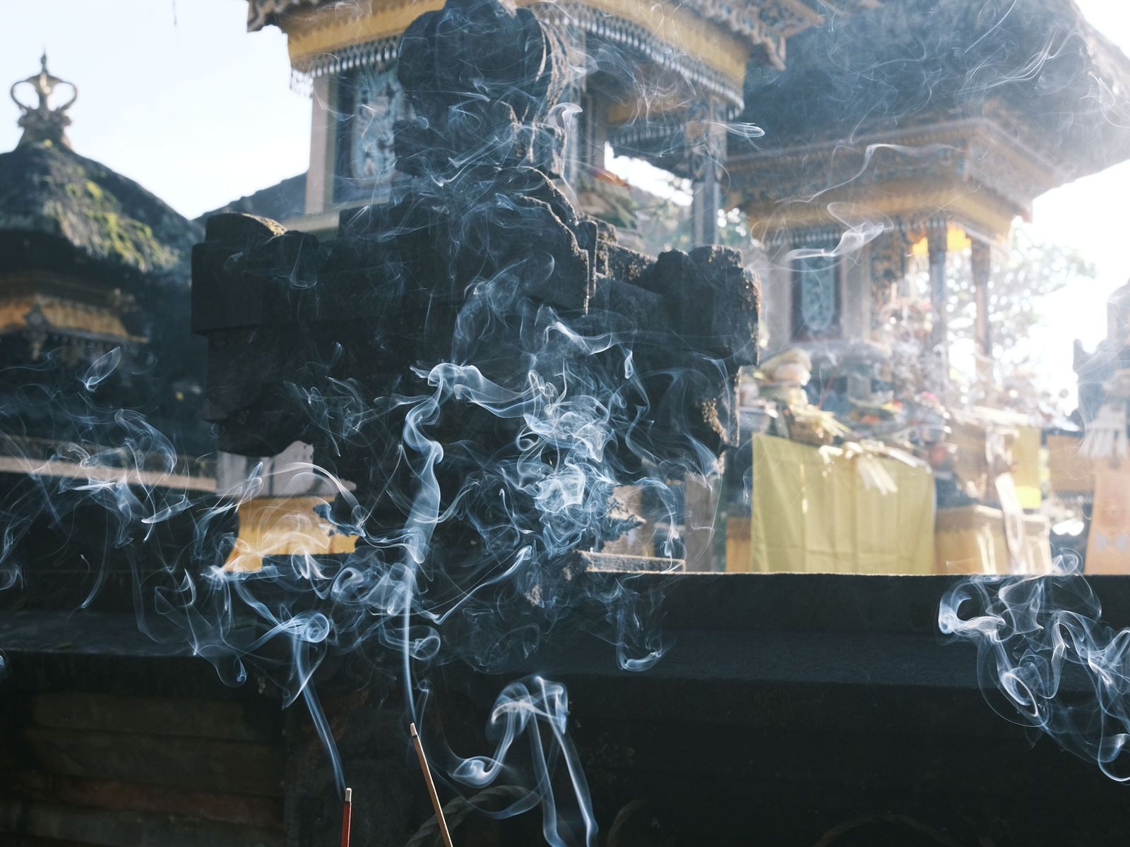Incense smoke rising over temple offerings