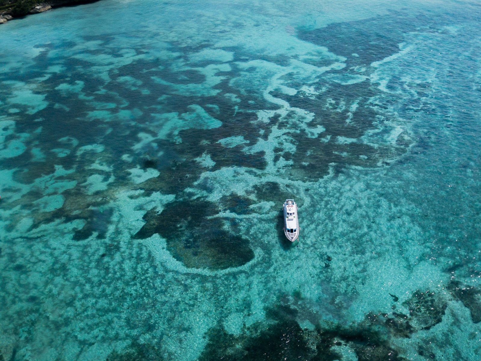 A boat over shallow reef, seen from the air