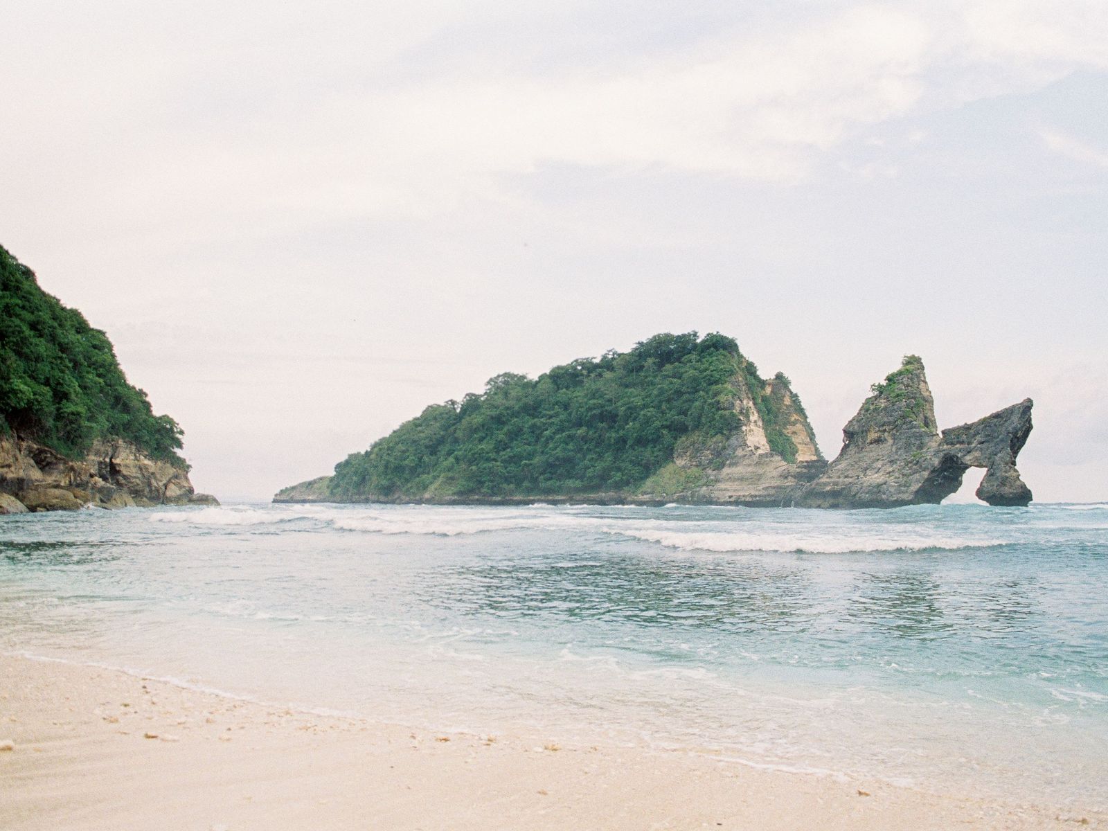 Atuh Beach at low tide, the arch island beyond